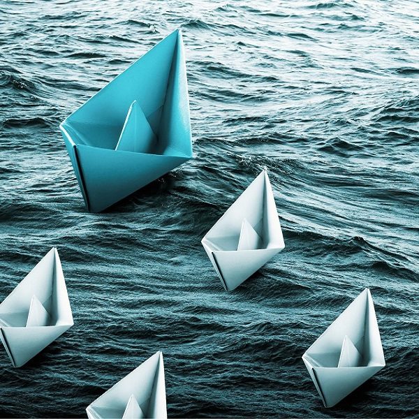 Papierschiffchen auf Wasser mit Führungsboot